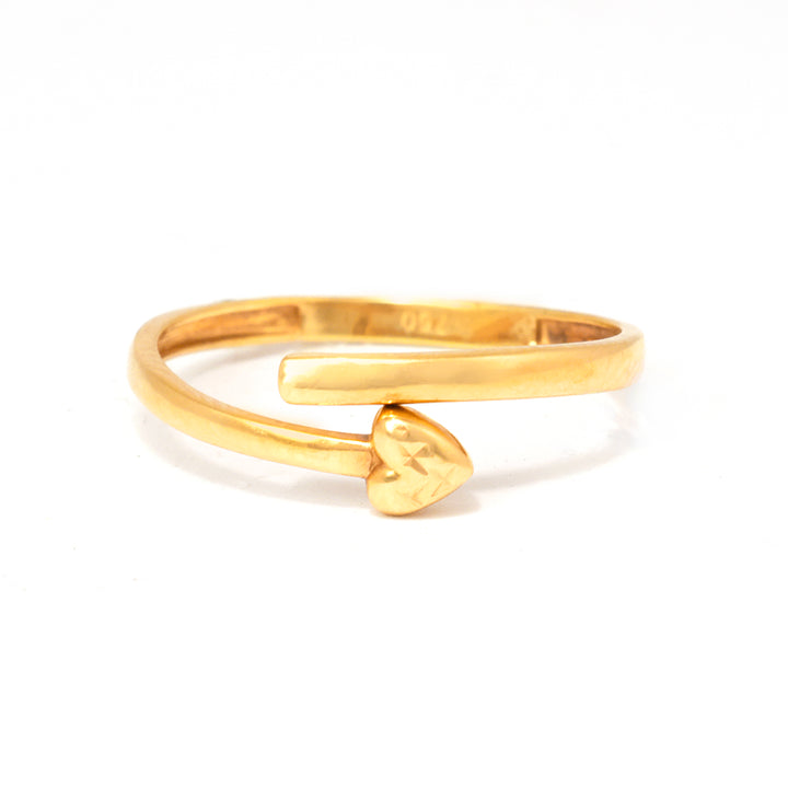 Gold open ring with a heart-shaped charm on a white background