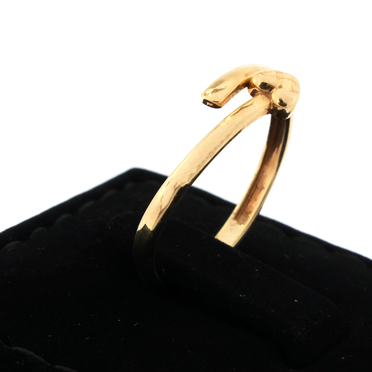 Gold ring with a unique design on a black cushion against a white background
