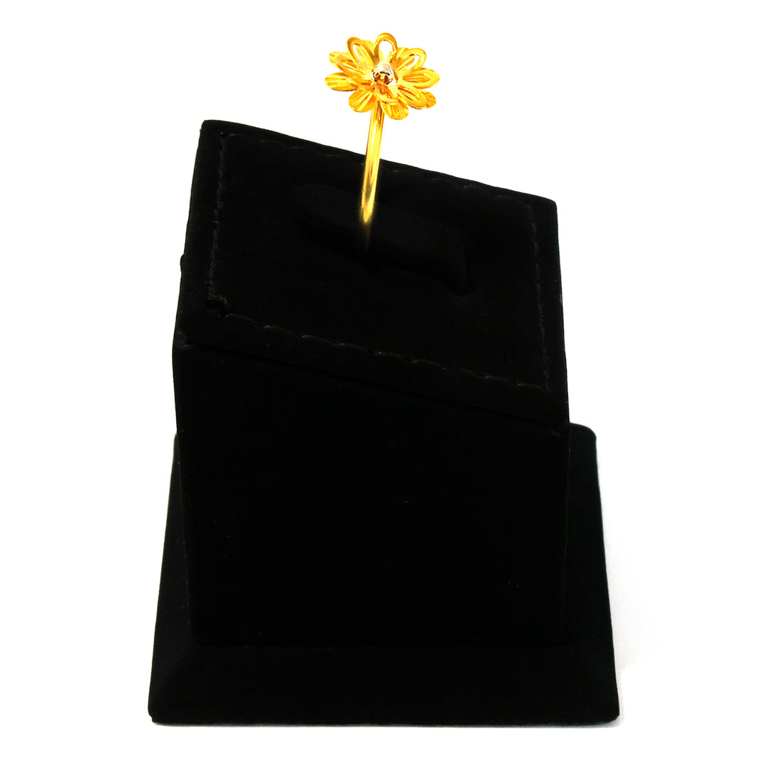 Gold flower-shaped earring on a black velvet stand against a white background