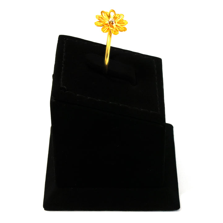 Gold flower-shaped earring on a black velvet stand against a white background