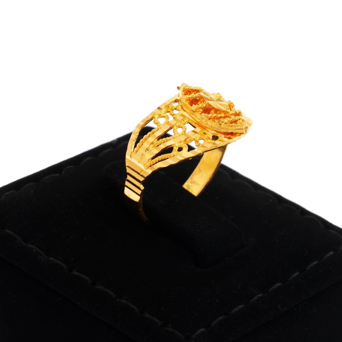 Gold ring with intricate design on a black cushion against a white background