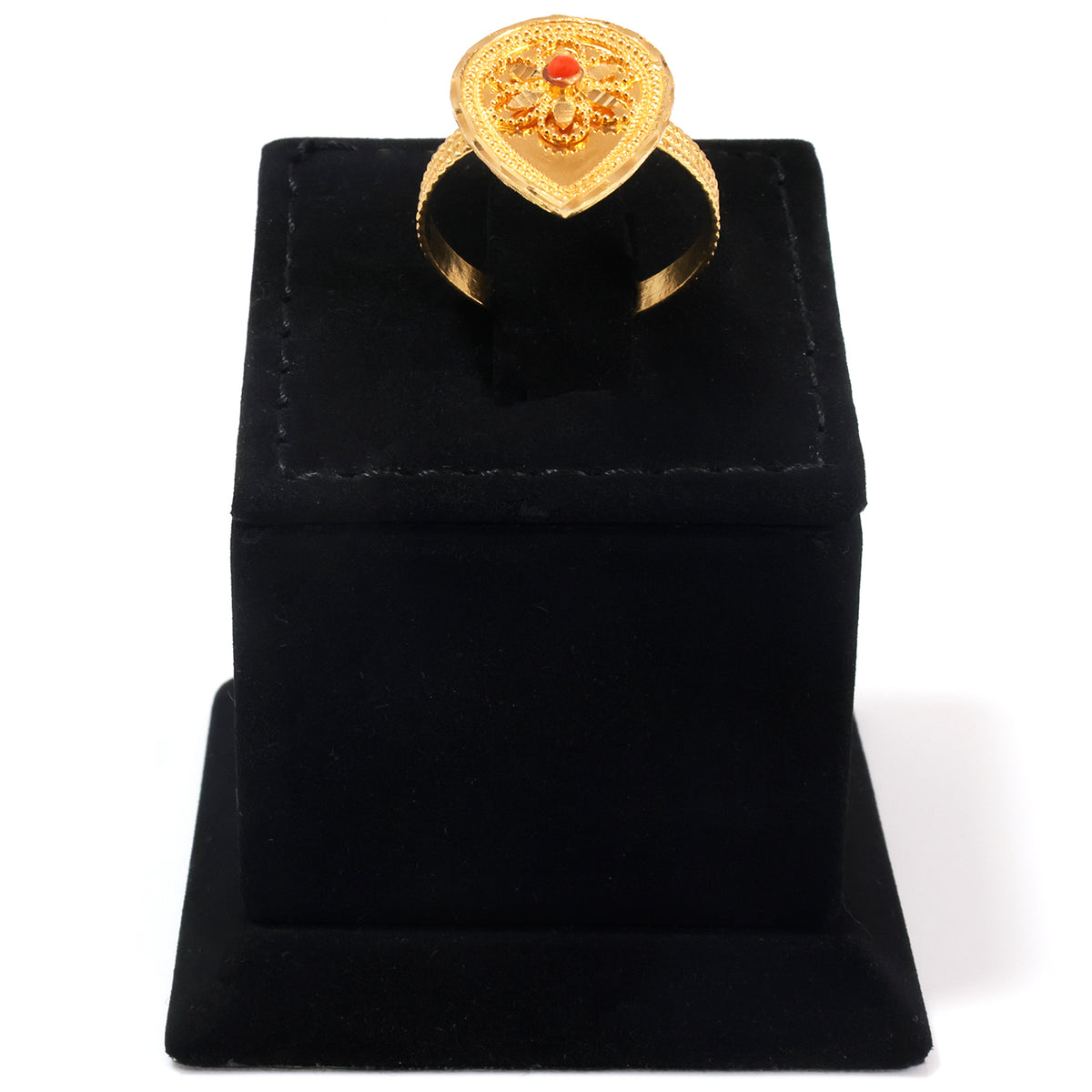 A gold ring with an ornate heart-shaped top and a small red center stone, displayed on a black velvet ring box against a white background.