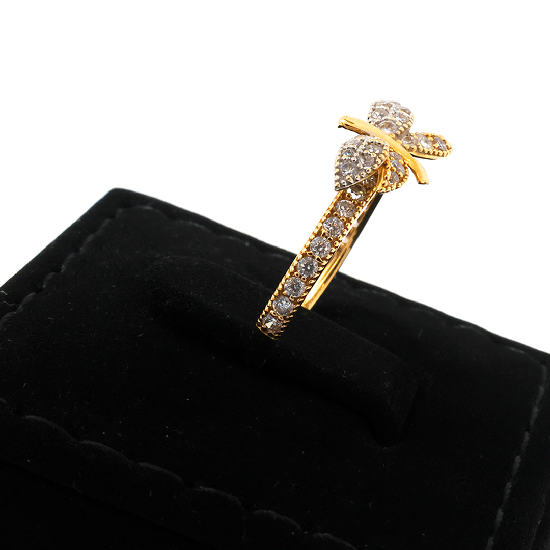 Gold bow-shaped brooch with gemstones on a black cushion
