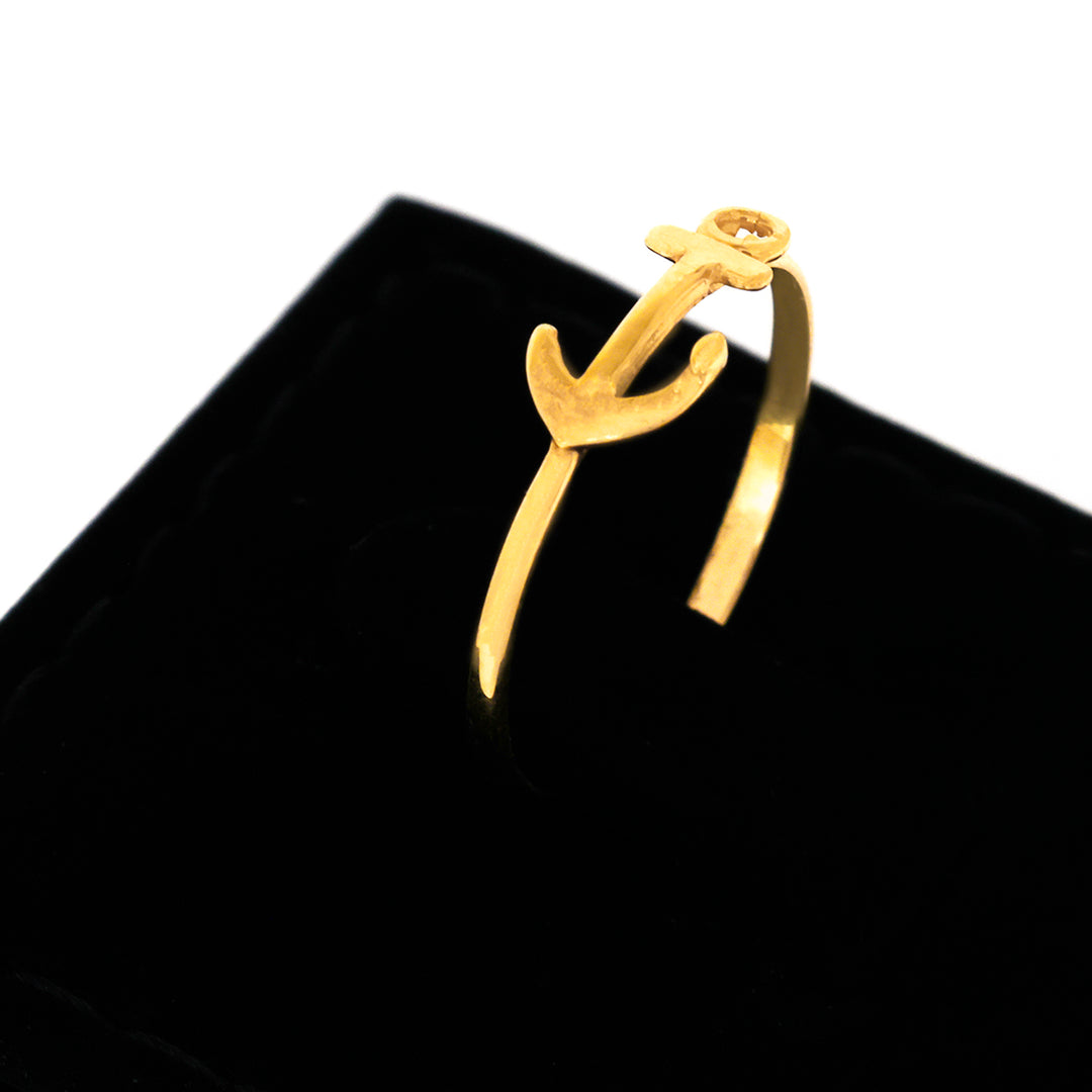 Gold anchor-shaped ring on a black velvet stand