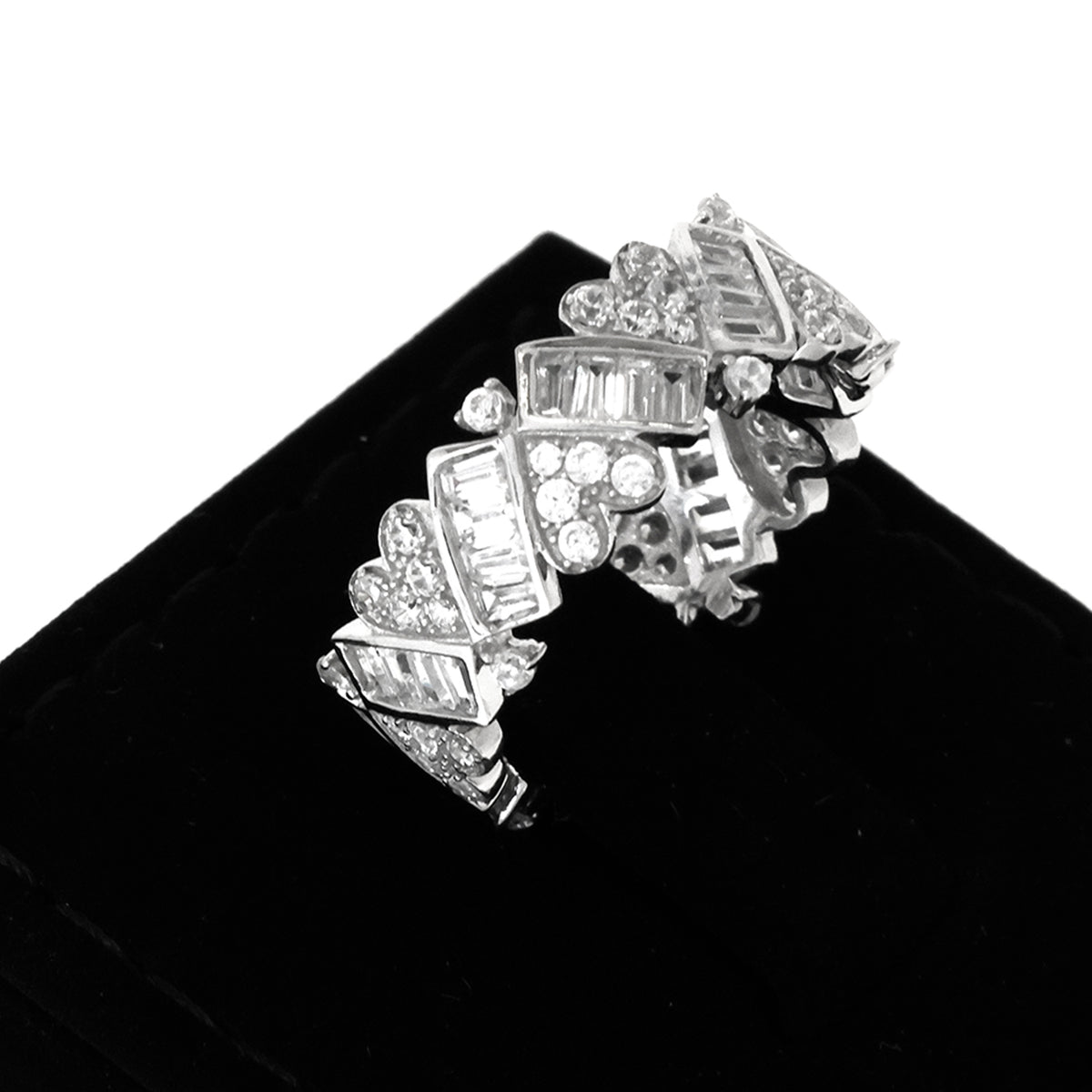 Silver ring with heart and diamond designs on a black stand