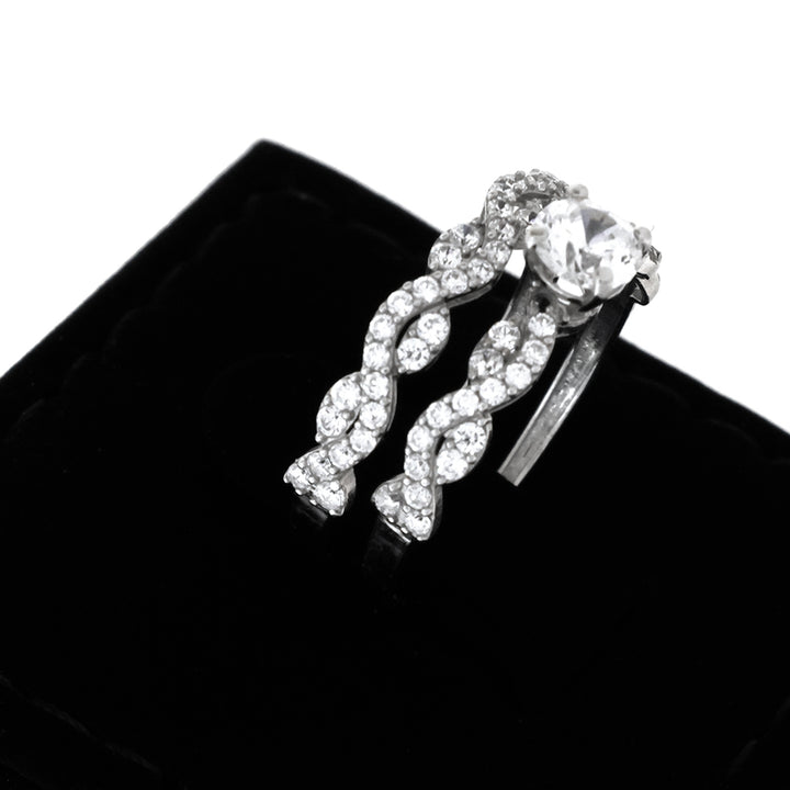 Silver ring with braided design and clear gemstone on a black background