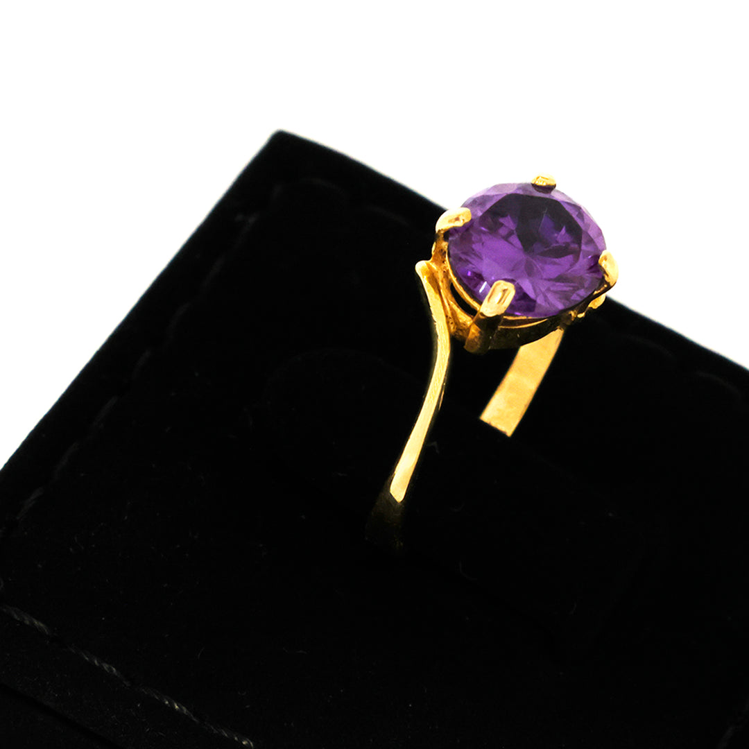 Gold ring with a purple gemstone on a black velvet background