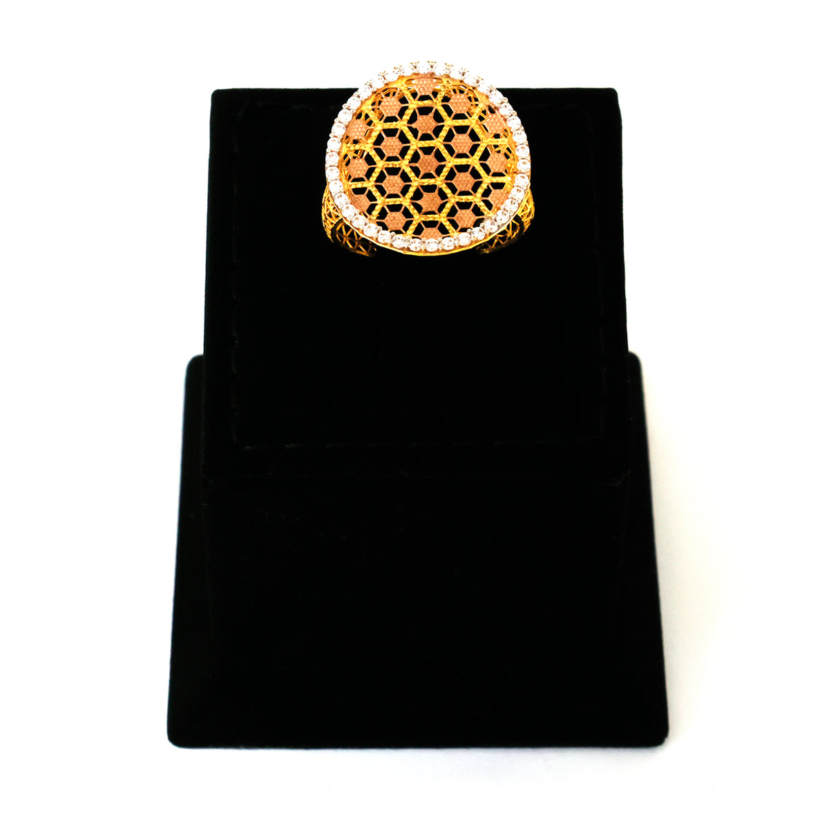 Gold ring with geometric design on a black stand against a white background