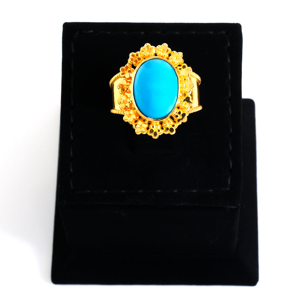 Gold ring with a blue gemstone on a black stand