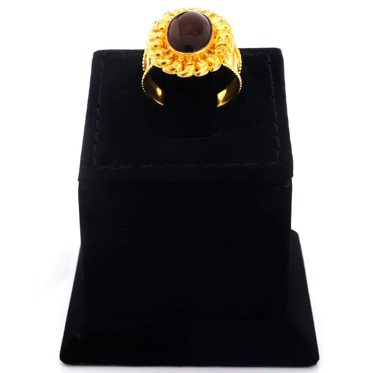 A gold ring with a large oval dark brown gemstone, displayed on a black velvet jewelry stand against a white background.