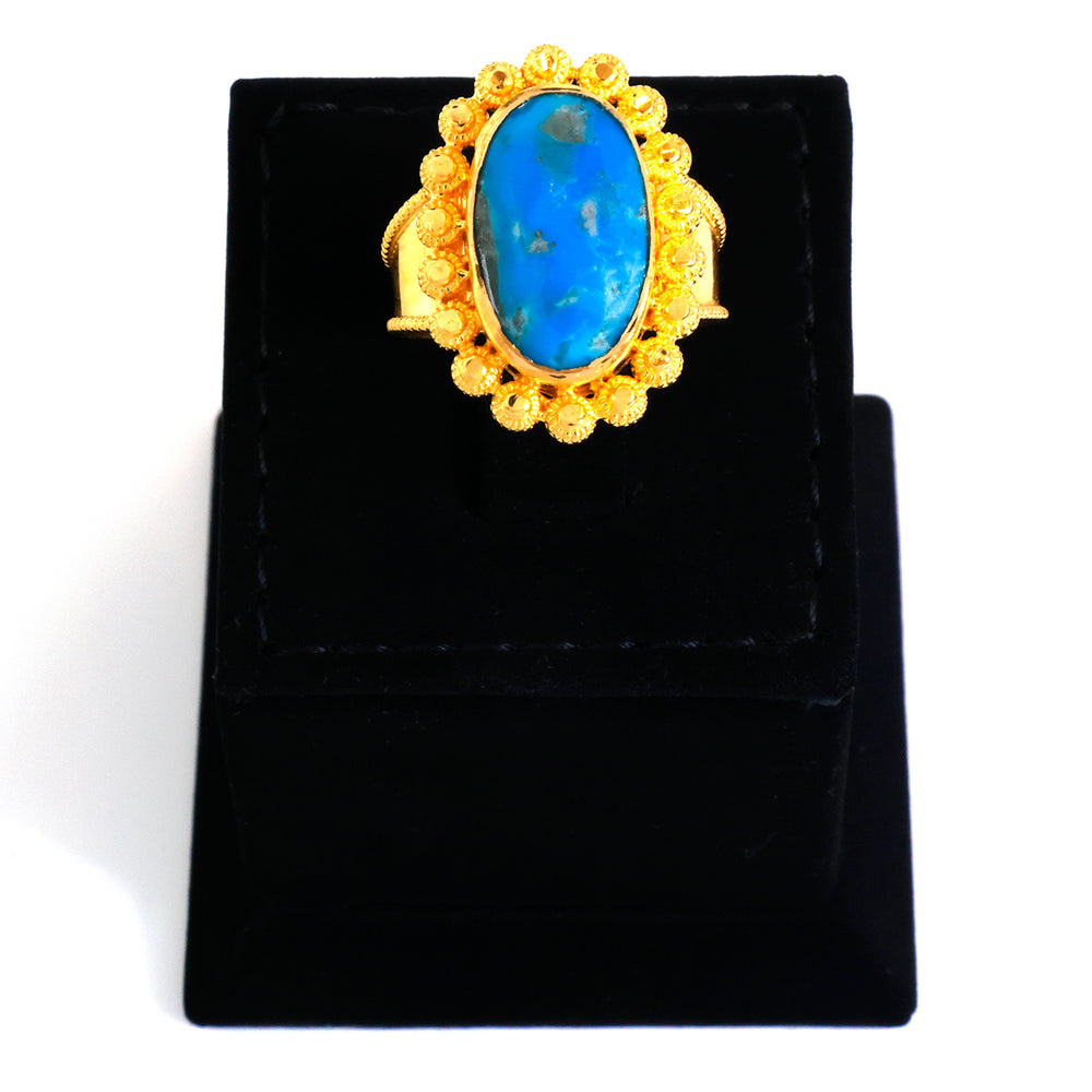 Gold ring with a blue stone on a black stand