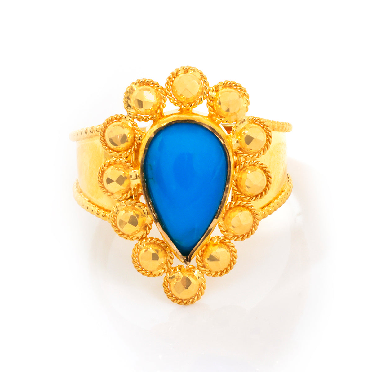 Gold ring with a blue teardrop stone on a white background