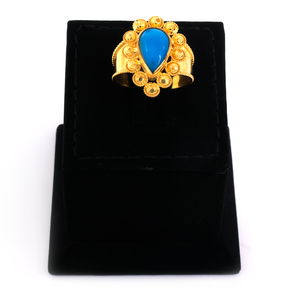 Gold ring with a blue stone on a black velvet stand