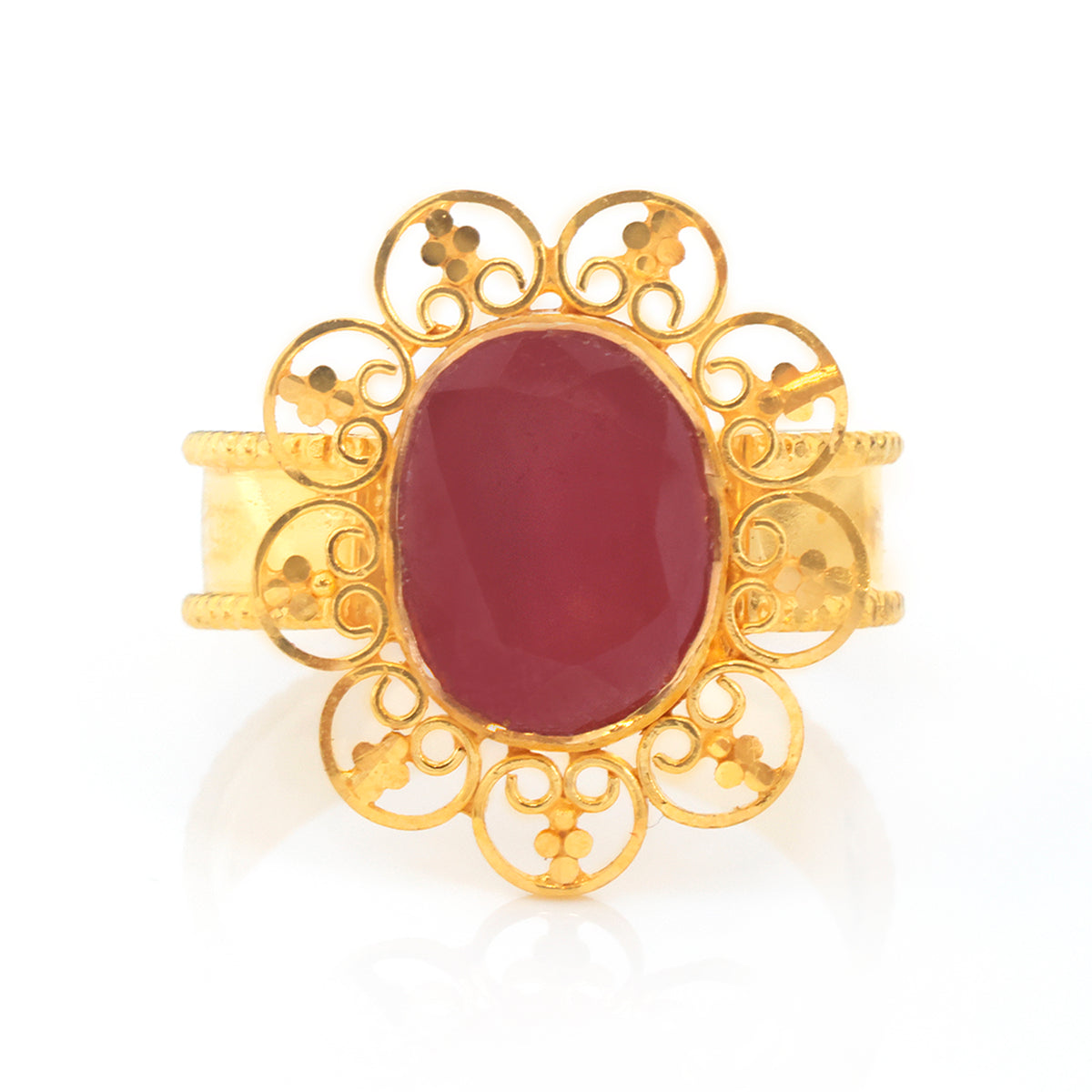 A gold filigree ring featuring an oval cabochon garnet gemstone, set against a clean white background with a soft reflection.
