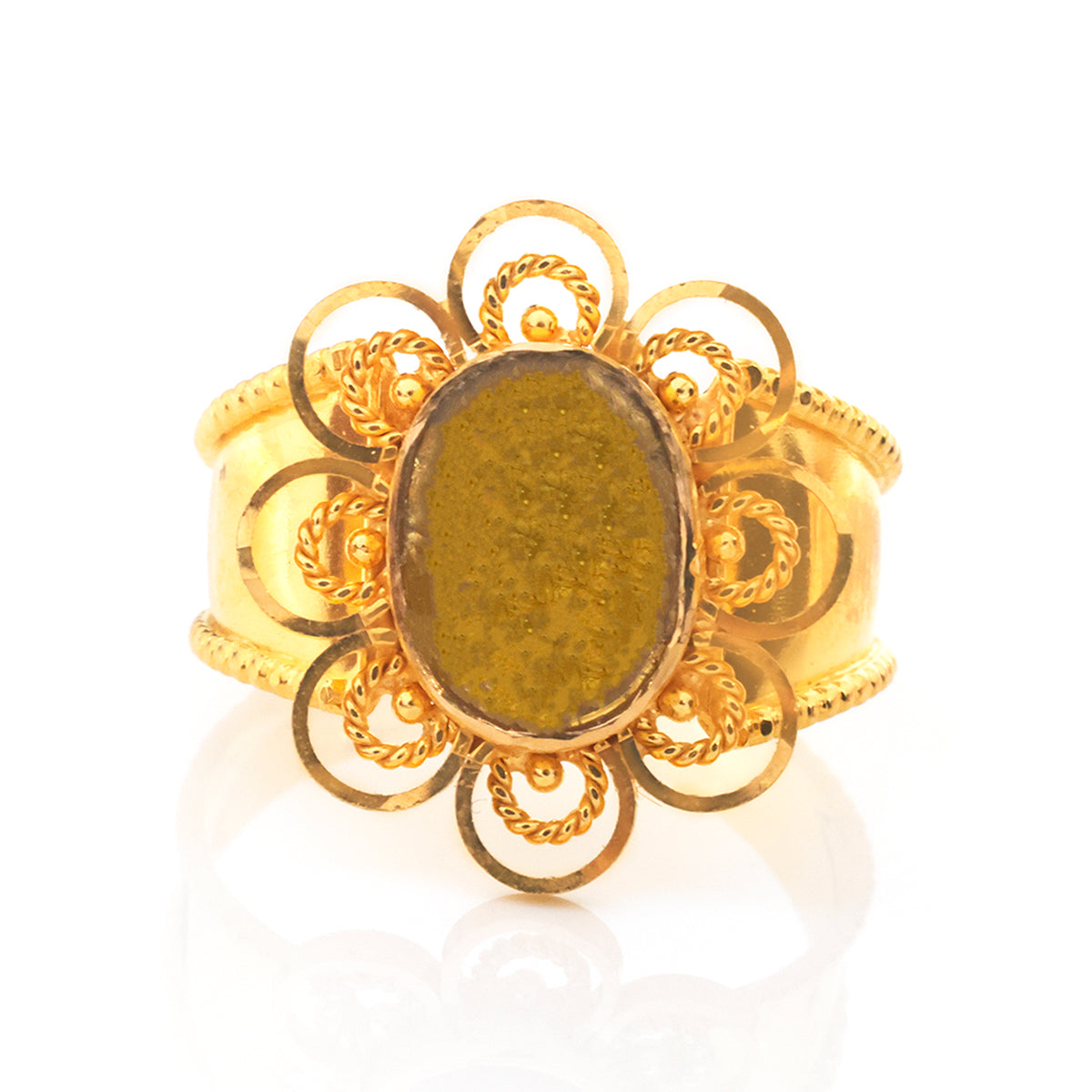 A vintage-style gold ring featuring an oval green stone in a decorative filigree setting with scrollwork and beaded details, shown on a white reflective background.