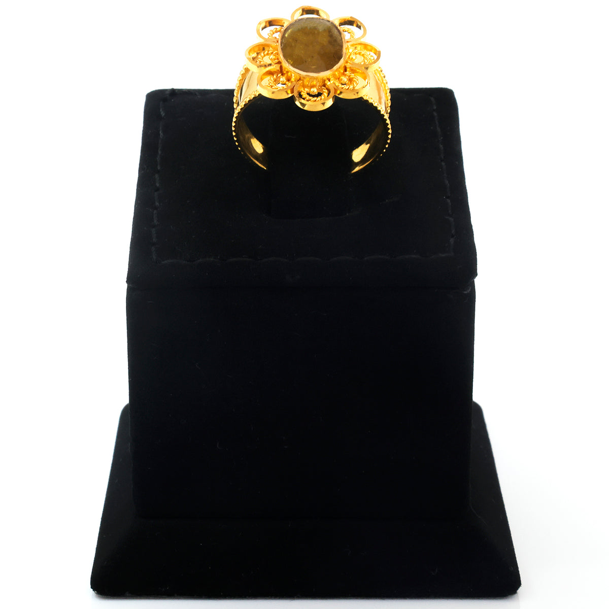 A gold ring with a large oval brown gemstone and decorative floral detailing, displayed on a black velvet ring box against a white background.