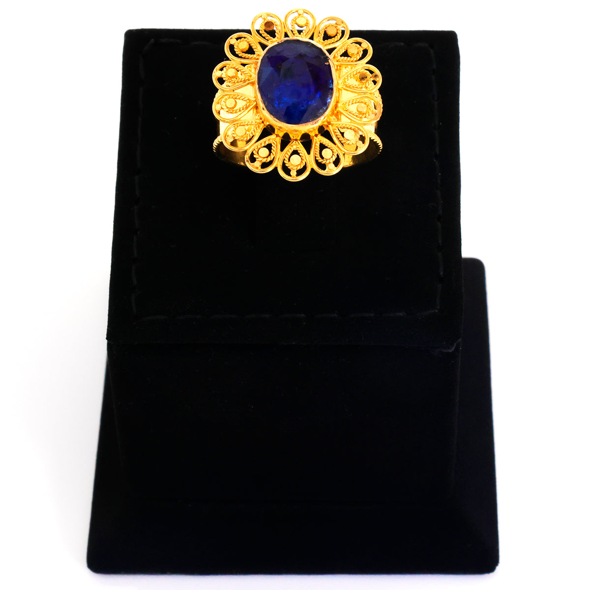 Gold ring with a blue gemstone on a black velvet stand