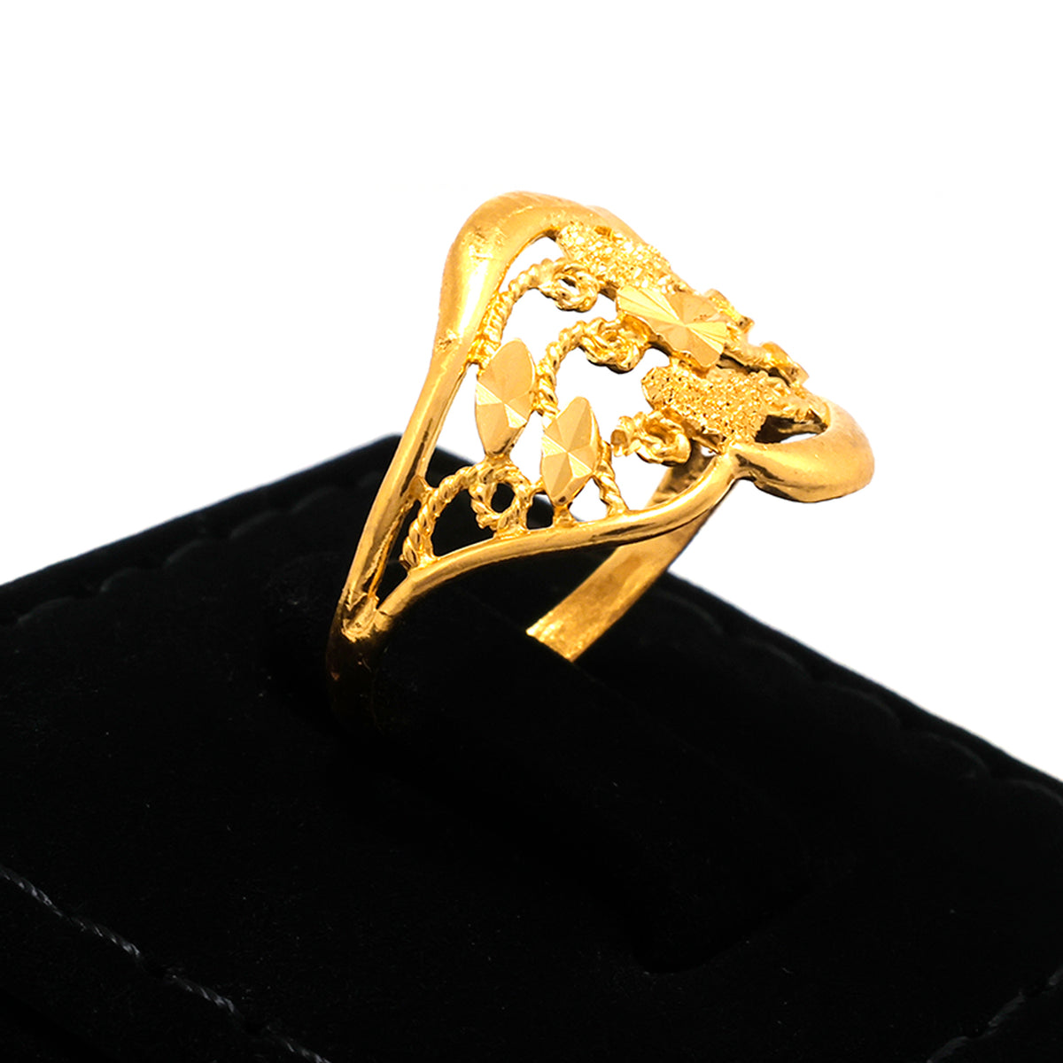 Gold ring with intricate design on a black cushion against a white background