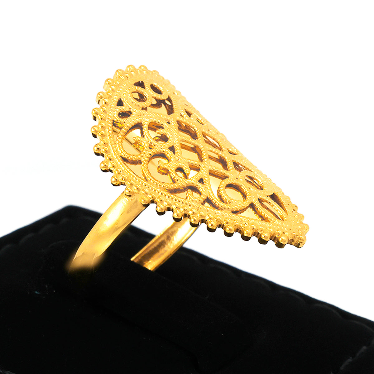 Gold ring with intricate design on a black cushion against a white background
