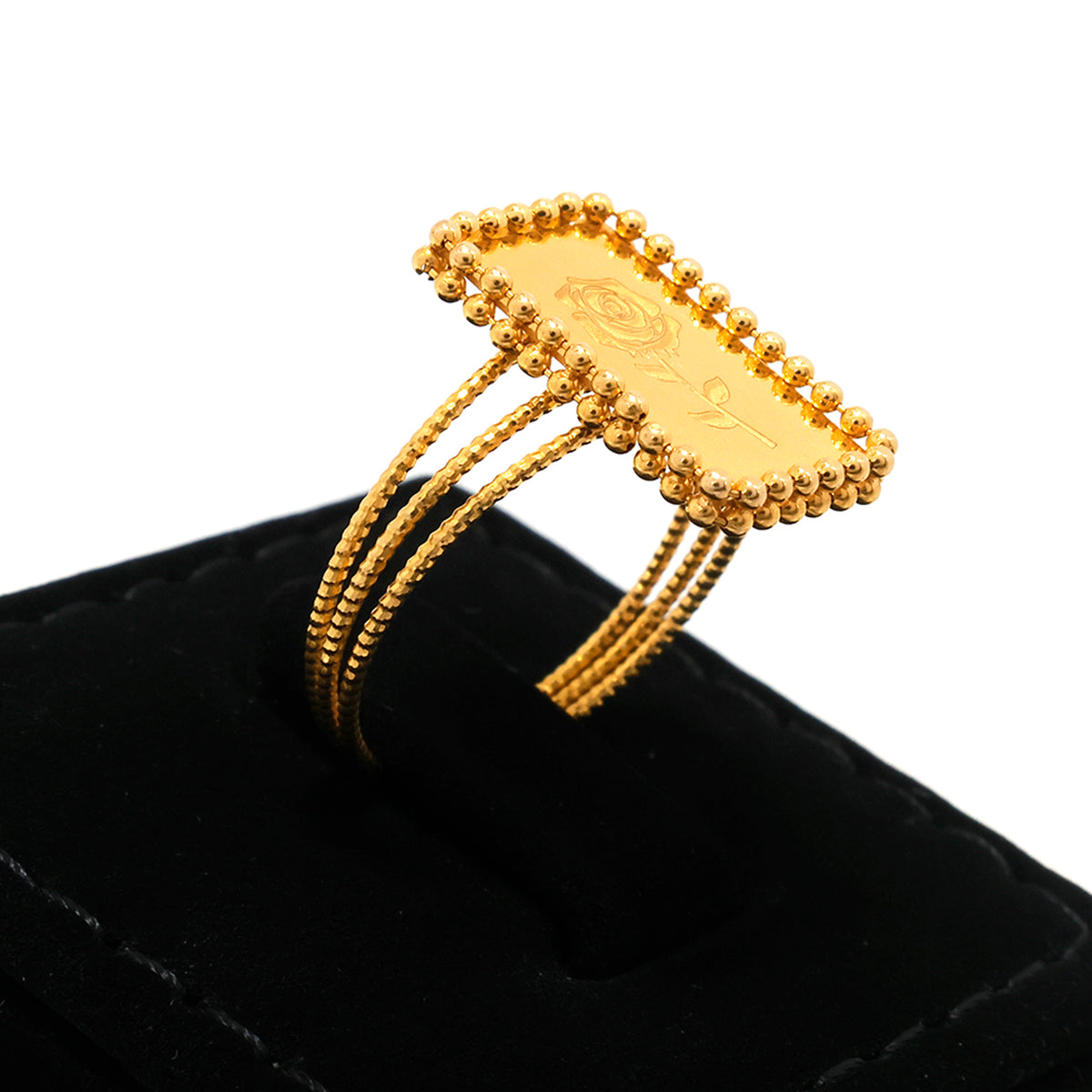 Gold bracelet on a black cushion with a white background