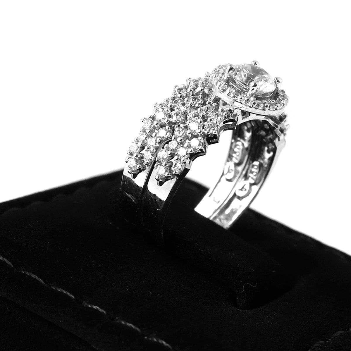 Silver ring with gemstones on a black stand against a white background