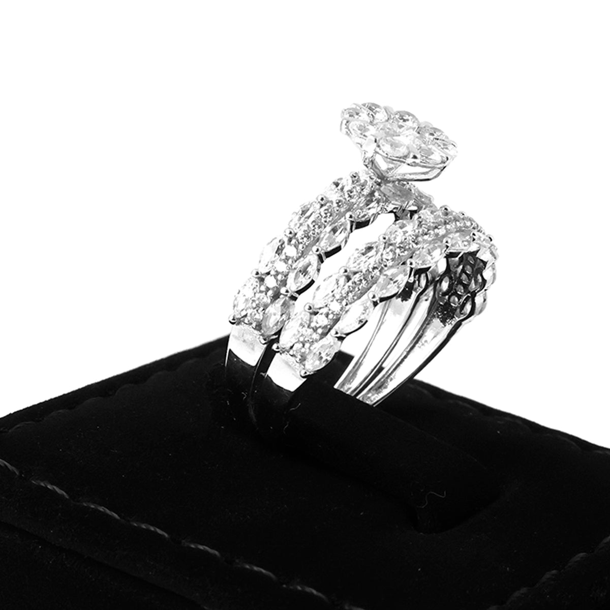 Silver ring with diamond accents on a black cushion against a white background