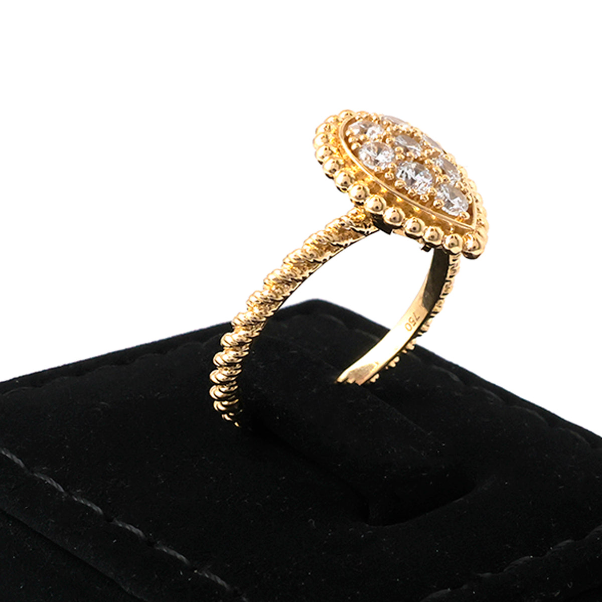 Gold ring with diamonds on a black cushion against a white background