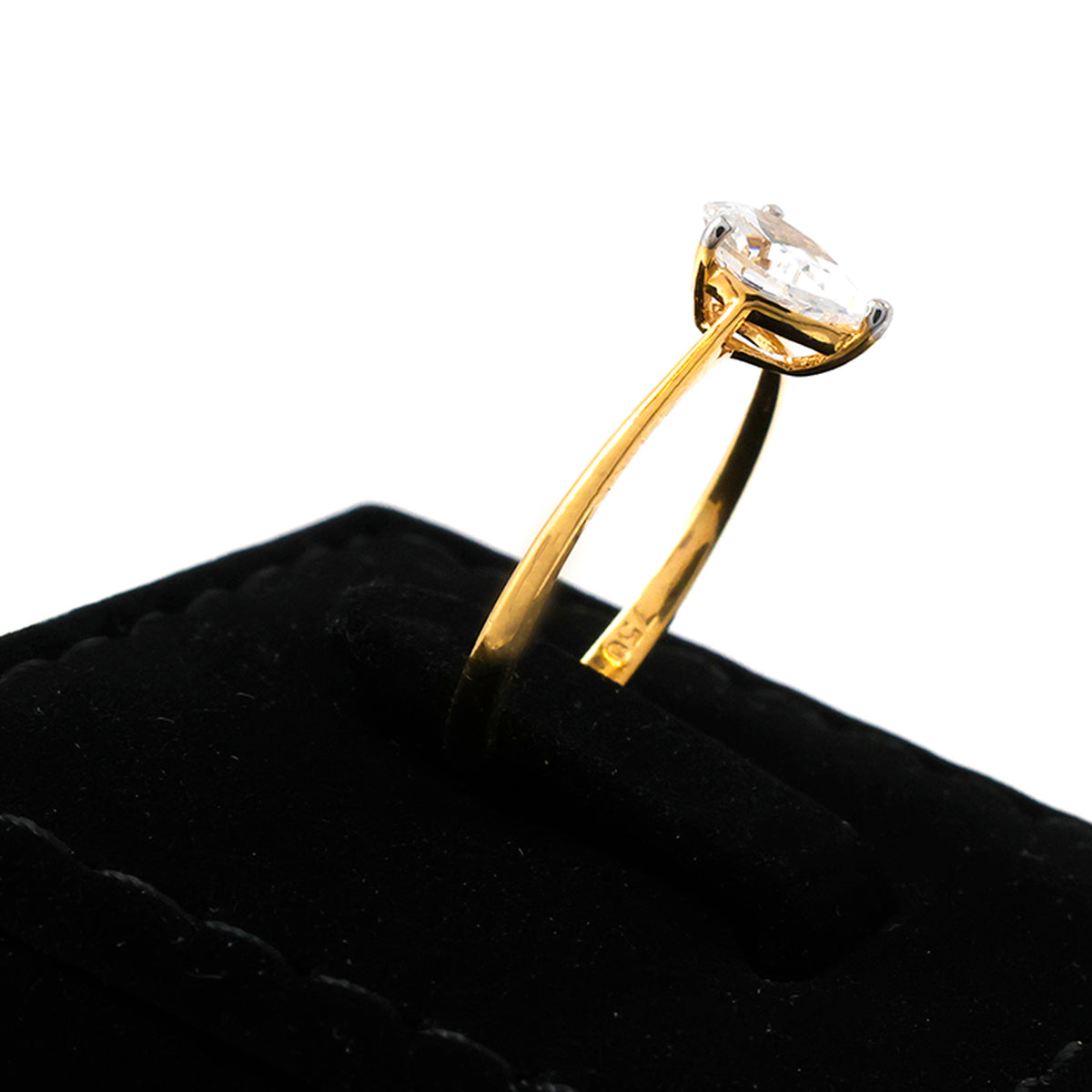 Gold ring with a diamond on a black cushion against a white background