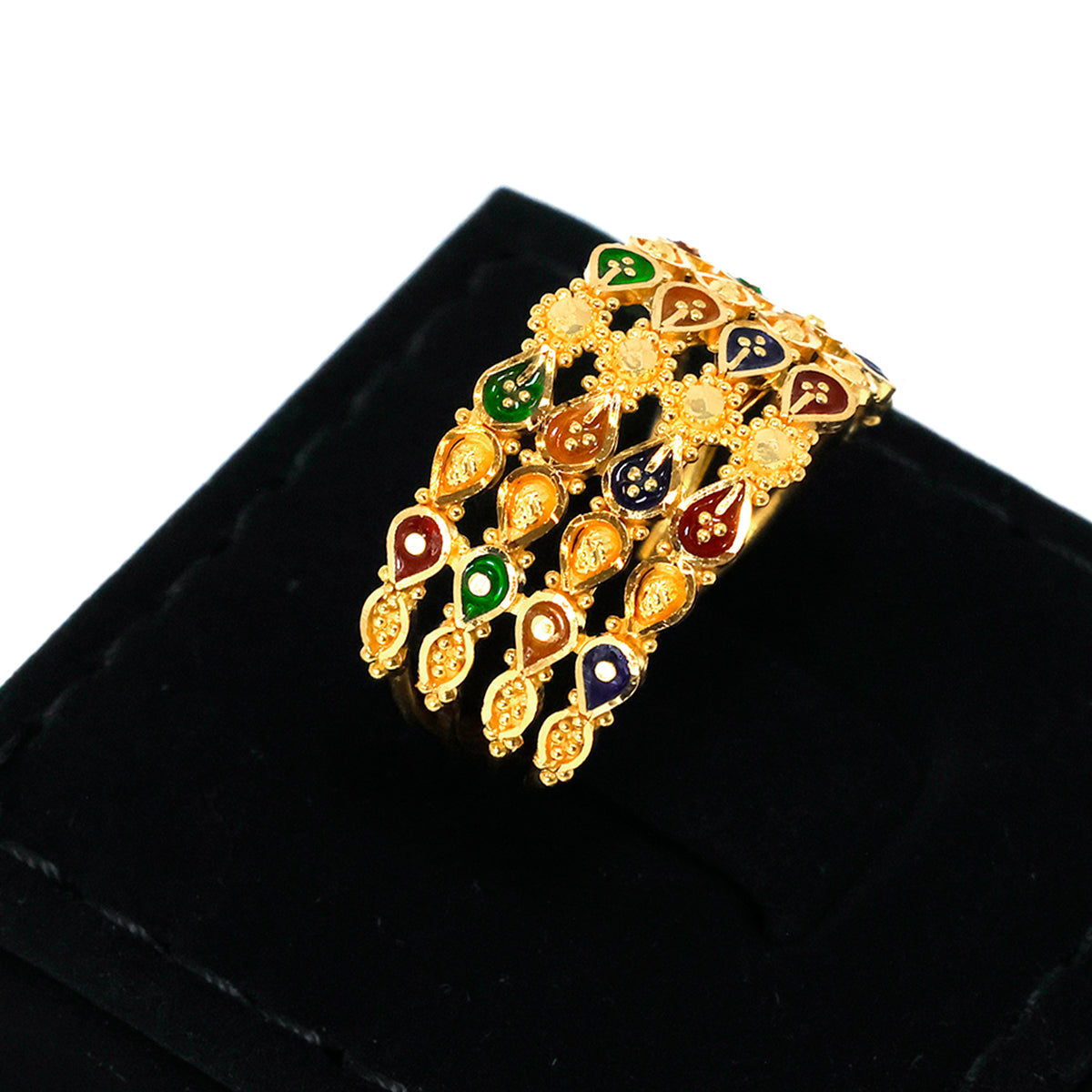 Gold bracelet with colored stones on a black velvet surface