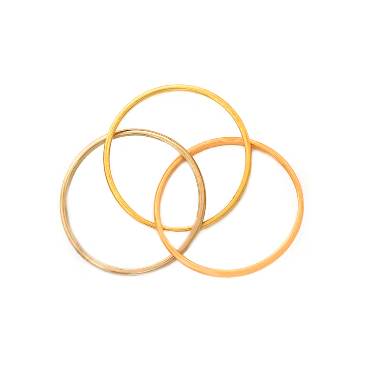 Three ذهب خواتم stacked on white background