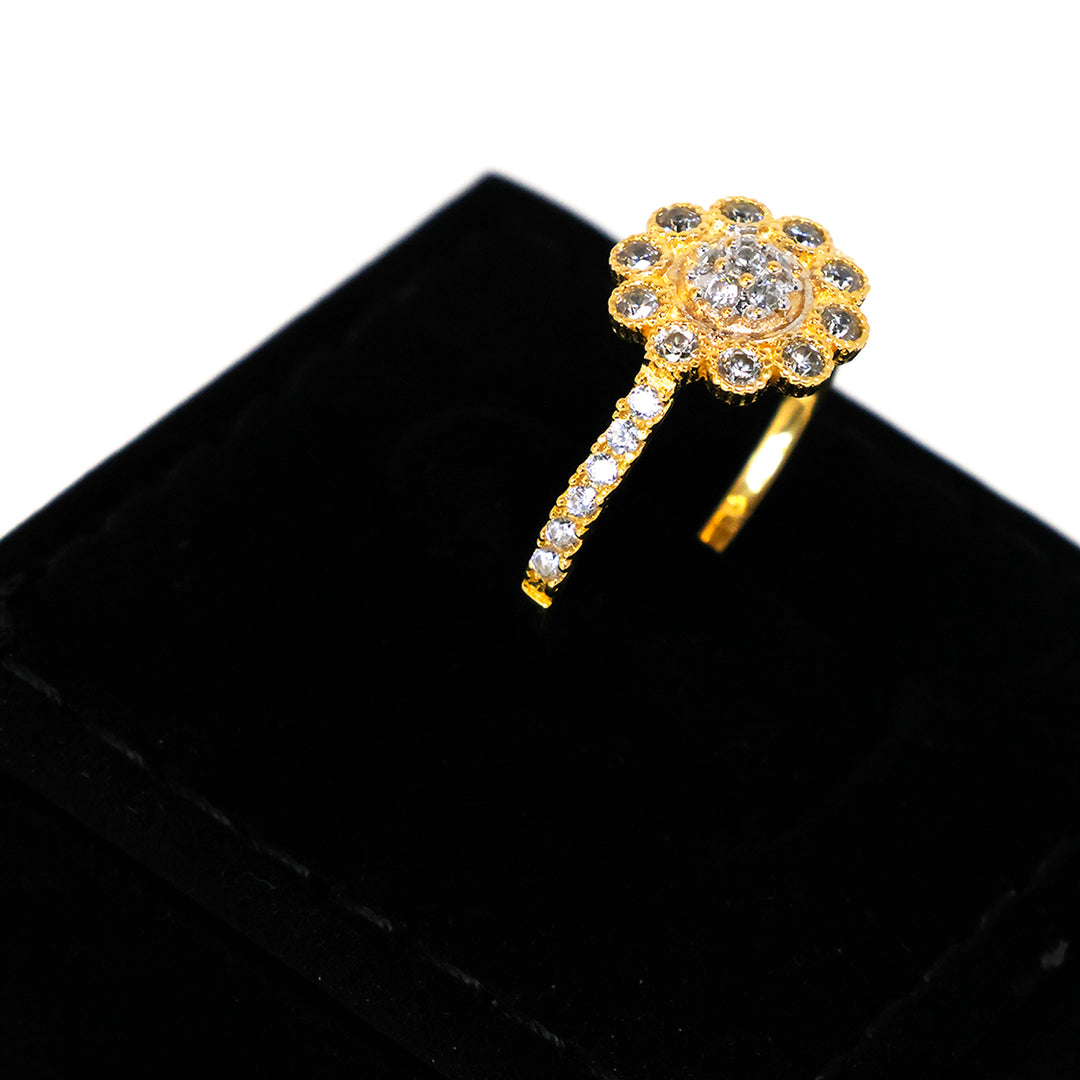 Gold ring with floral design and clear stones on a black background