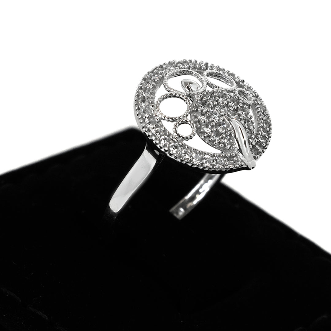 Silver ring with intricate design on a black stand against a white background
