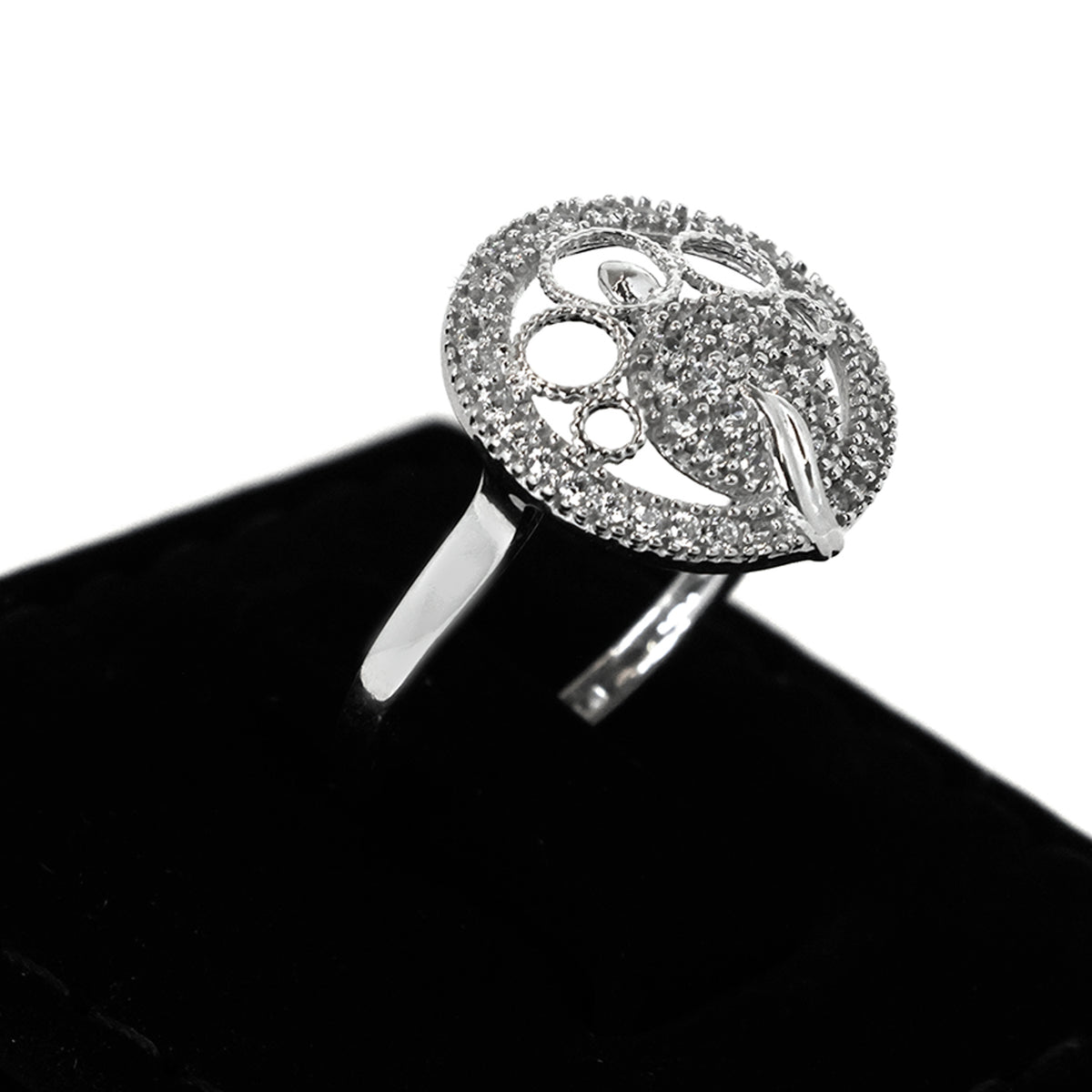 Silver ring with intricate design on a black stand against a white background