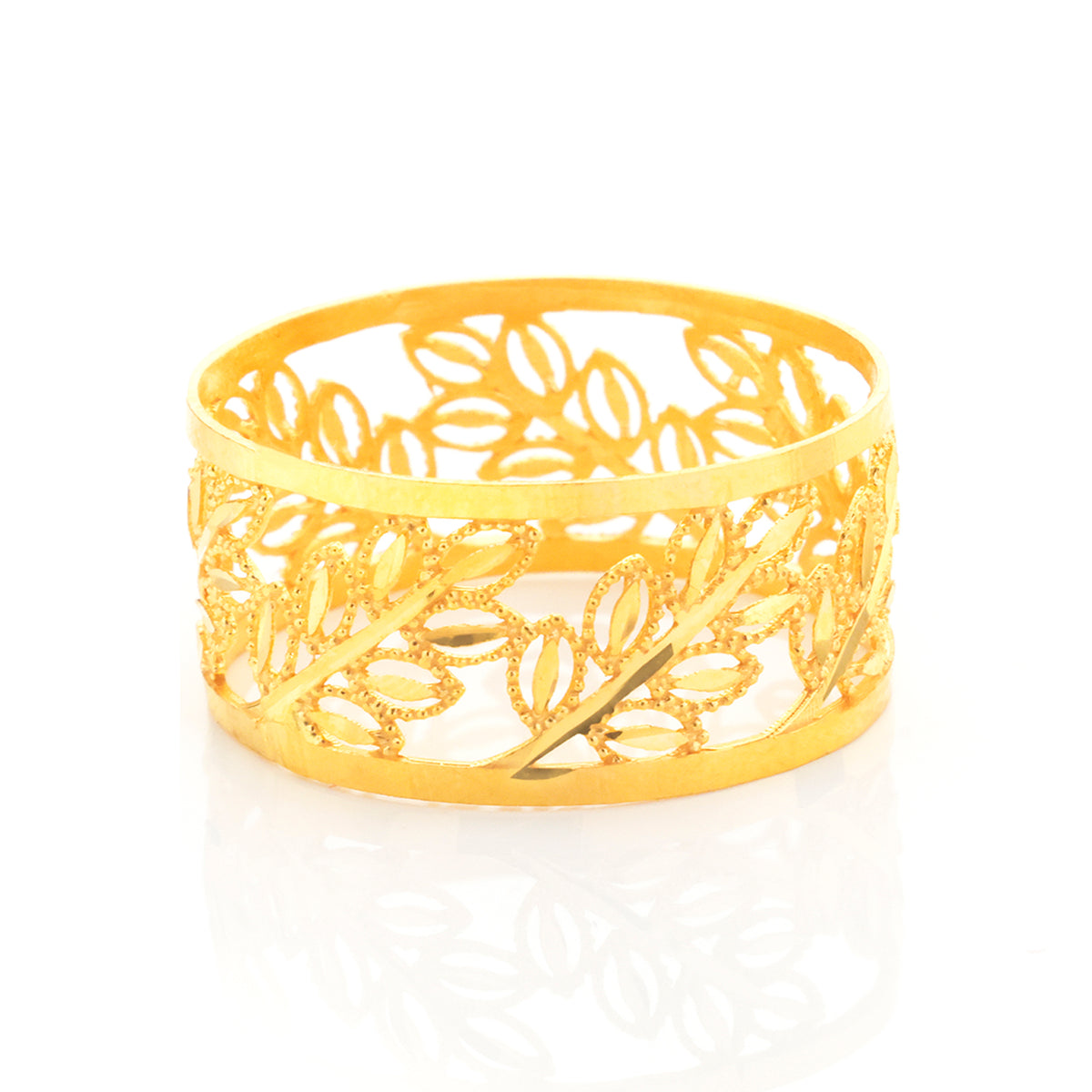 A gold filigree cuff bracelet with an intricate leaf pattern, displayed on a clean white background with a soft reflection underneath.