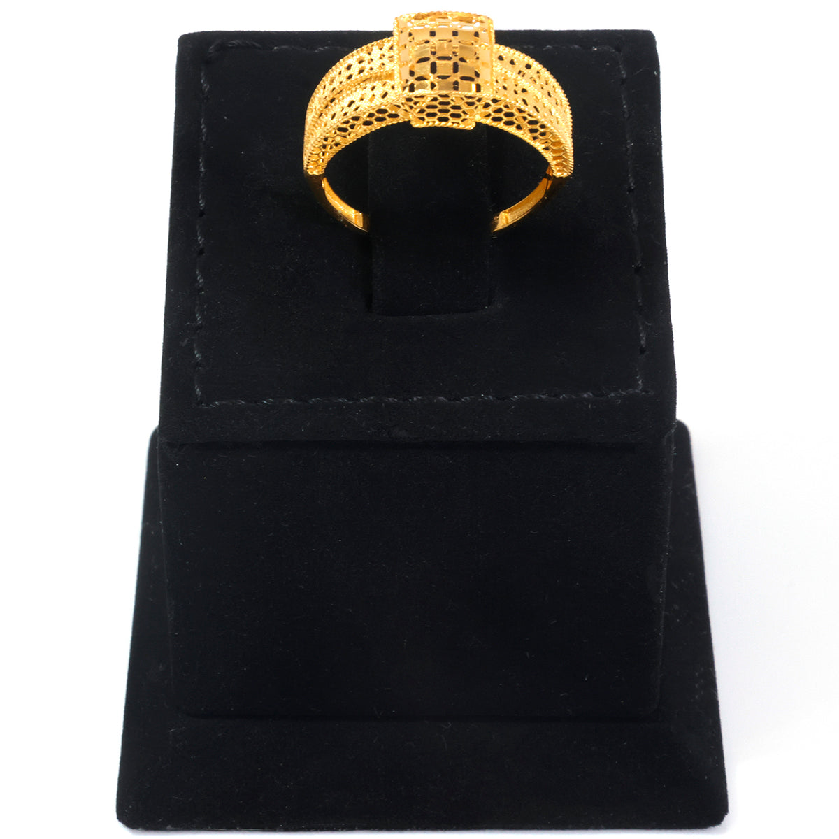 A gold ring with an intricate geometric, honeycomb-like textured band, displayed on a black velvet ring box against a white background.