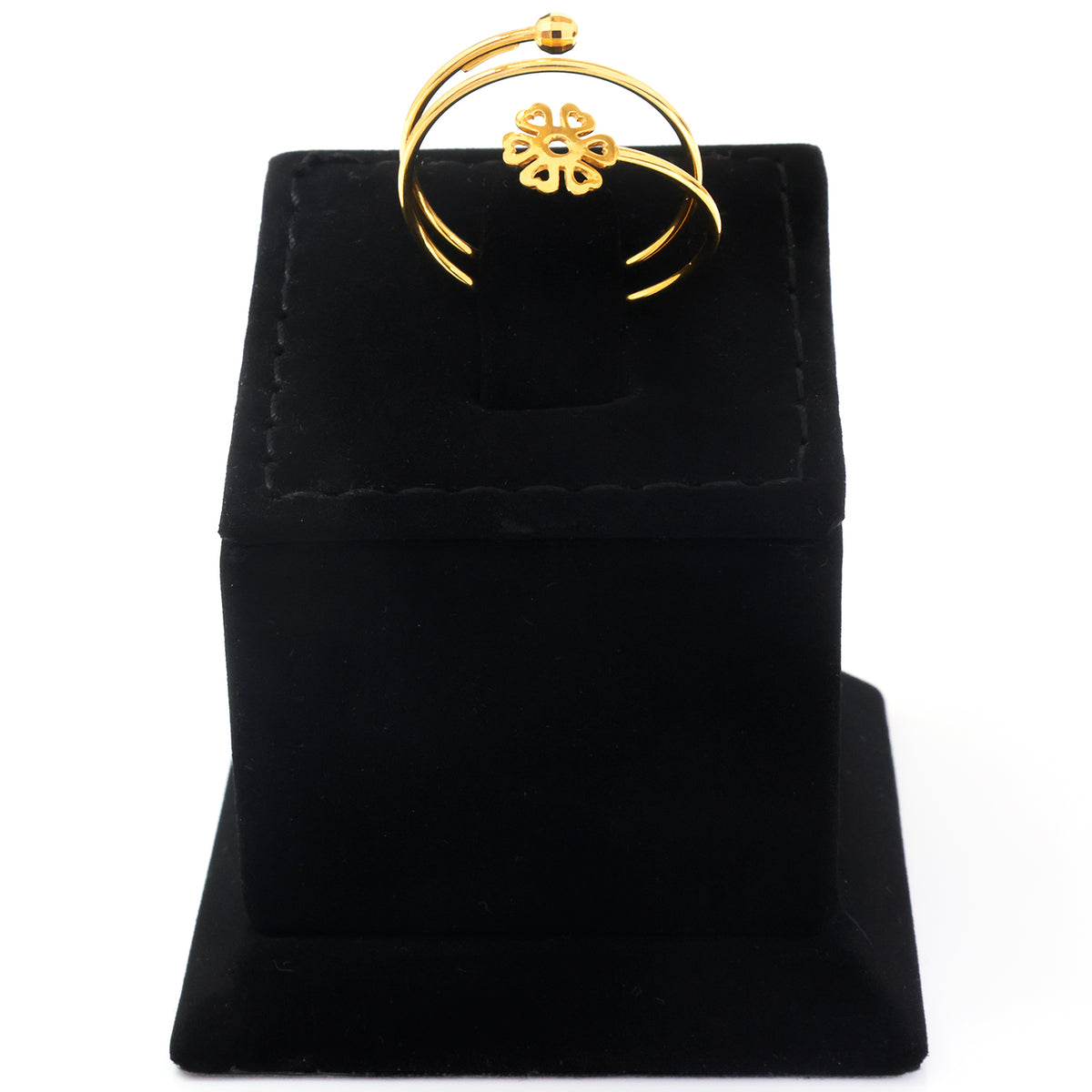 A gold ring with a small flower motif in the center, displayed on a black velvet jewelry stand against a white background.