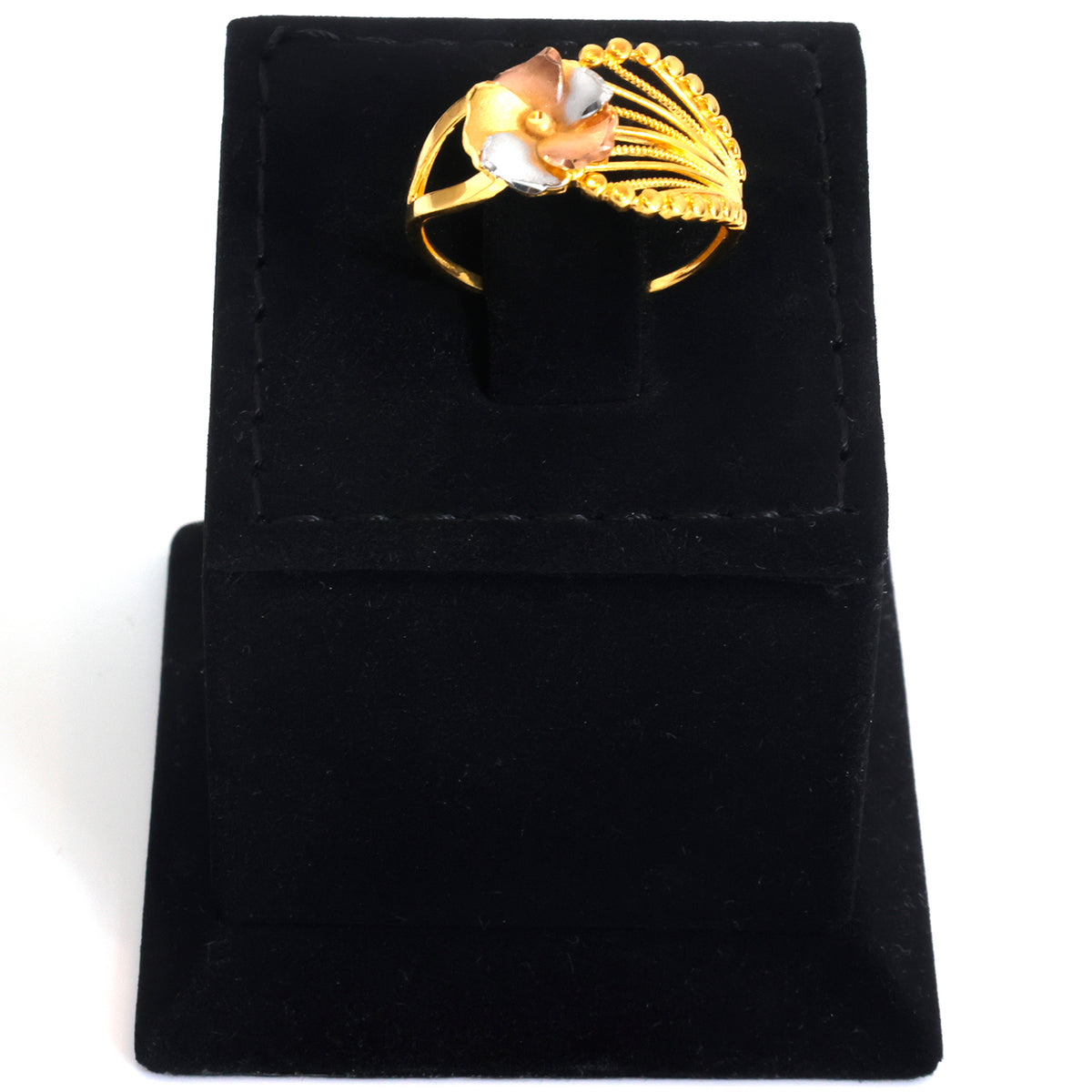 A gold ring with a floral design and a white inlay, displayed on a black velvet ring box against a white background.