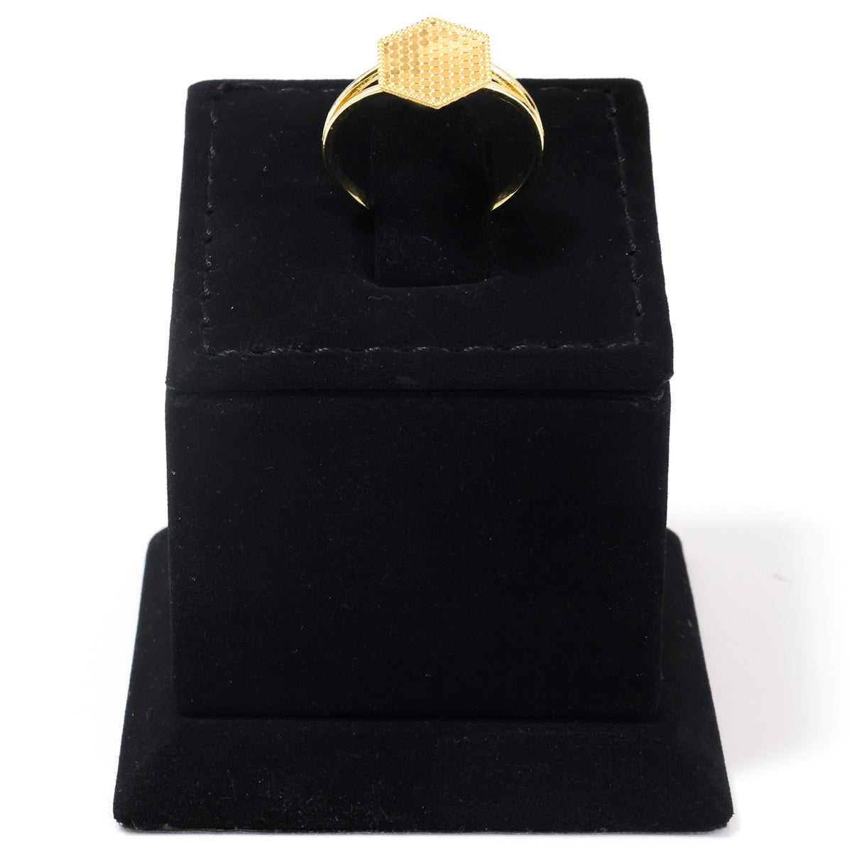 A gold ring with a textured geometric hexagonal face, displayed on a black velvet ring box against a white background.
