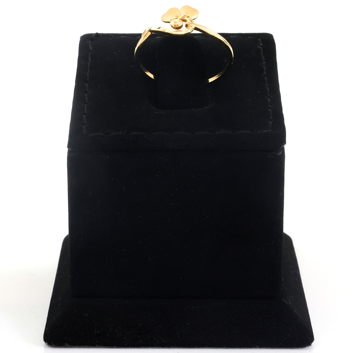 A gold ring with a small flower-shaped charm, displayed on a black velvet jewelry box against a white background.