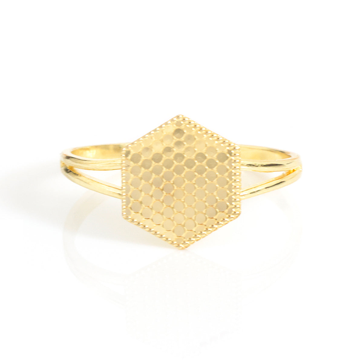 A gold hexagonal ring with a textured honeycomb pattern on the face and a polished band, shown on a clean white background with a soft reflection.