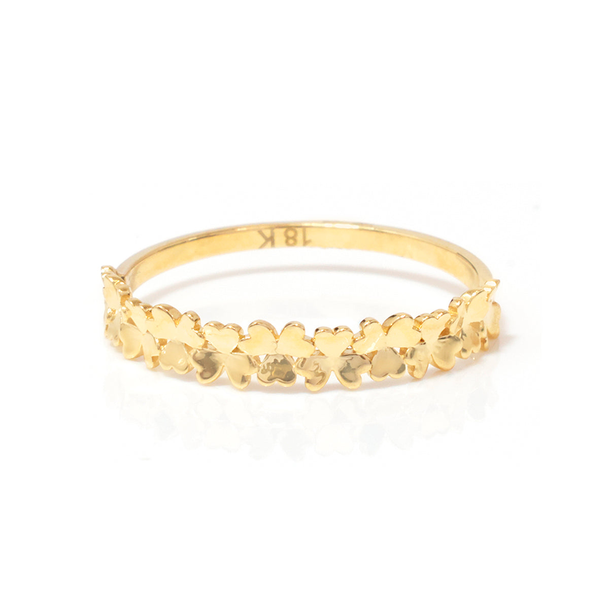 A gold band ring decorated with a row of small, textured flower petals, photographed on a clean white background with a soft reflection.