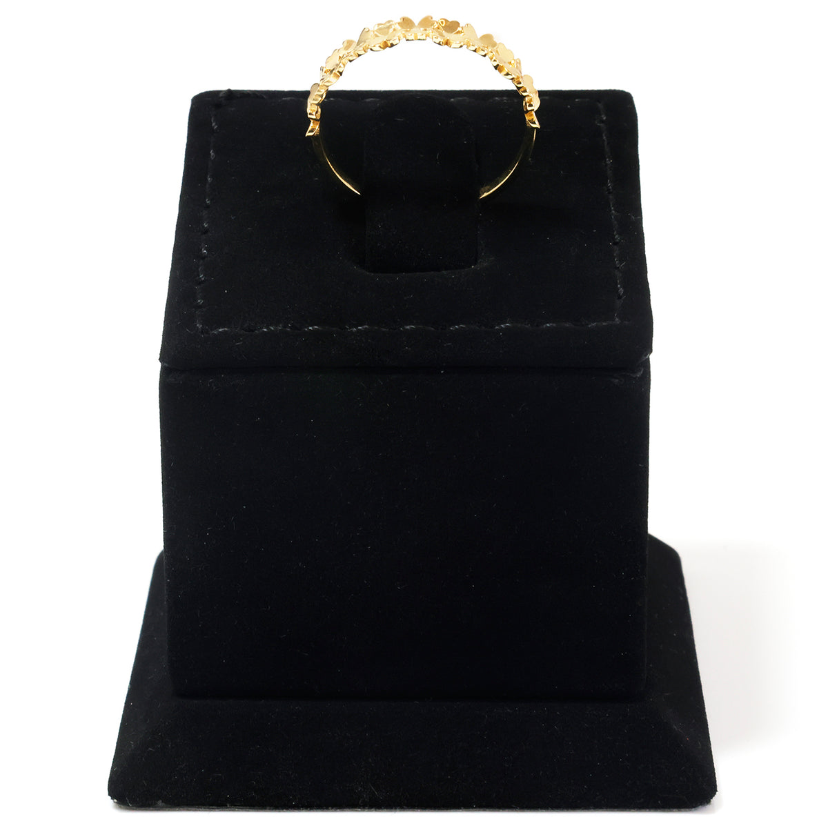 A gold ring with a textured, flower-like patterned band, displayed on a black velvet jewelry box against a white background.