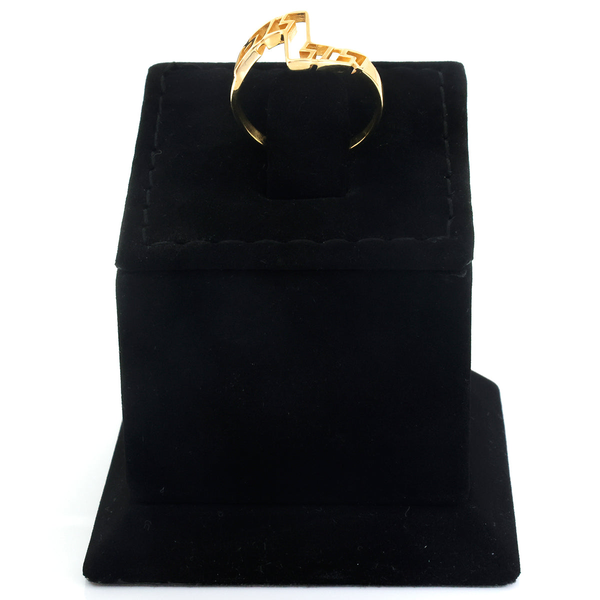 A gold ring with a textured, geometric openwork band displayed on a black velvet ring box against a white background.