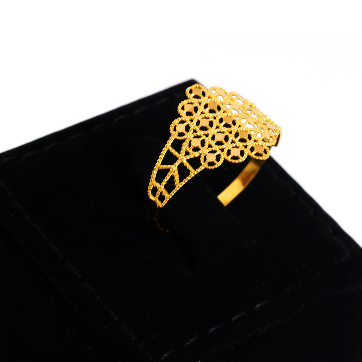 A gold ring with an intricate openwork filigree design, displayed on a black velvet ring box against a white background.