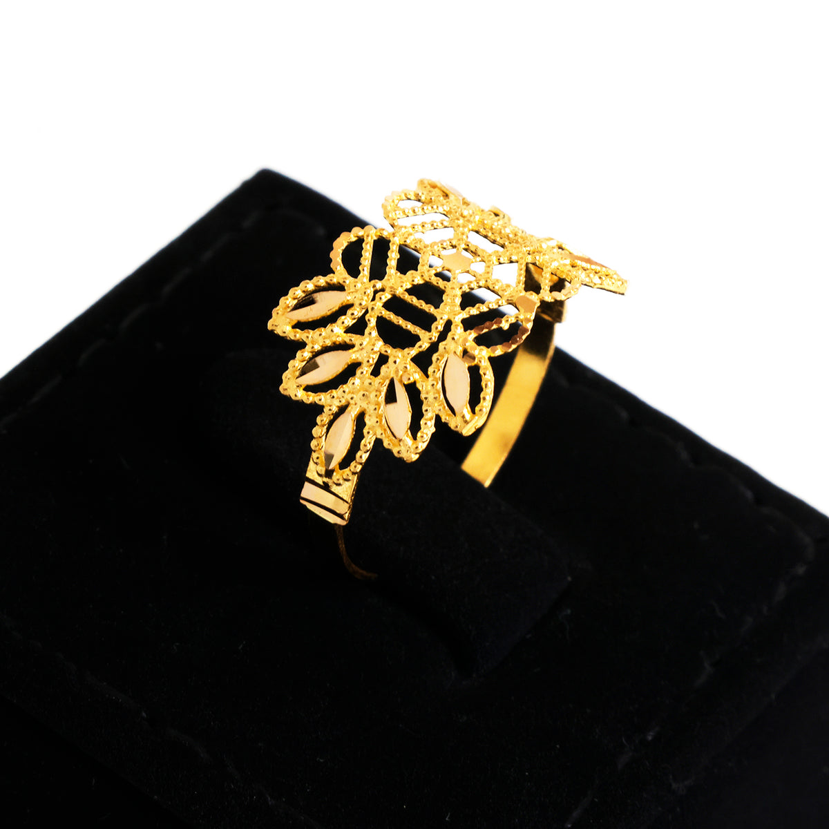 A gold ring with an intricate filigree leaf design, displayed on a black velvet ring box against a white background.