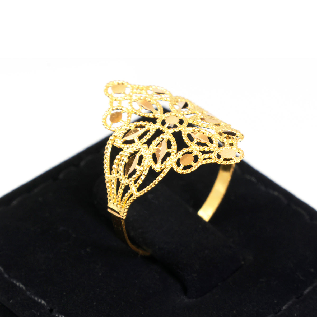 A gold filigree ring displayed on a black velvet ring box against a white background.