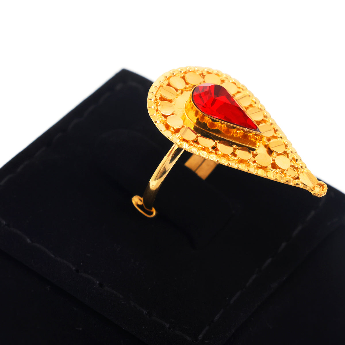 A gold ring with a teardrop-shaped textured setting and a central red teardrop gemstone, displayed on a black ring box against a white background.