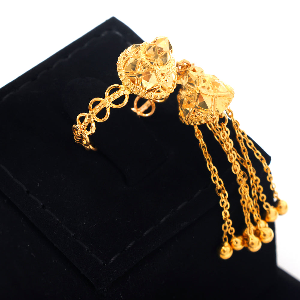 A gold-toned ornate bracelet displayed on a black jewelry stand against a white background. The bracelet features two faceted bead-like tops connected by curved chain links, with multiple dangling chain strands ending in small round beads.