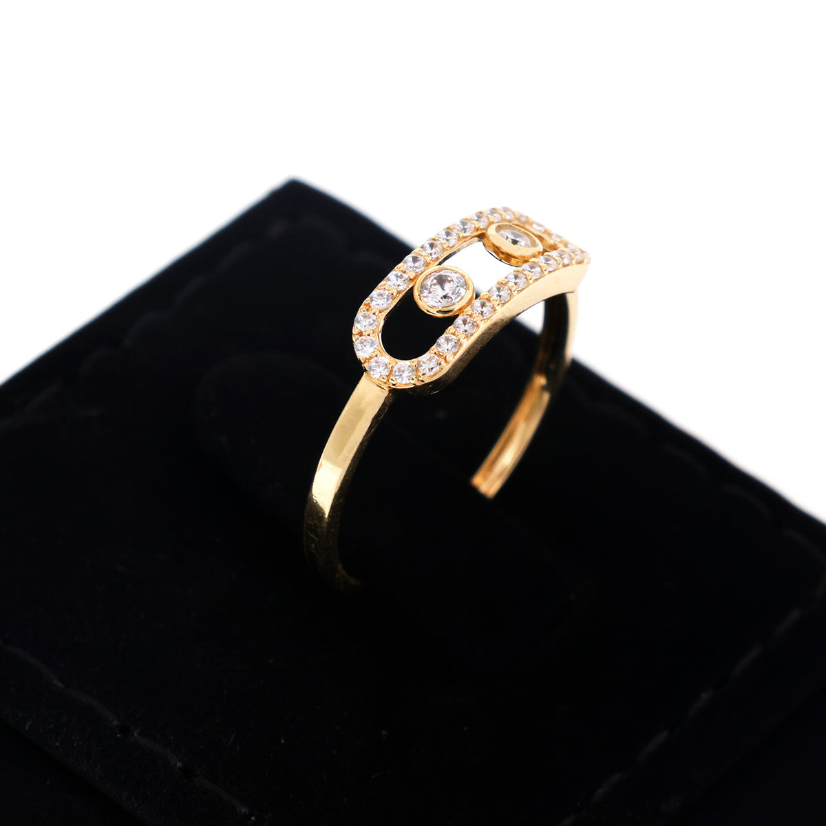A gold ring with a decorative open oval top set with clear stones, displayed on a black velvet ring box against a white background.