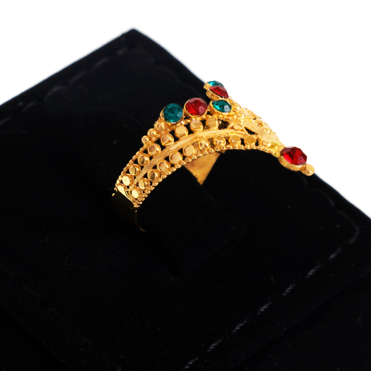 A gold crown-shaped ring with red and green gemstones, displayed on a black velvet ring box against a white background.